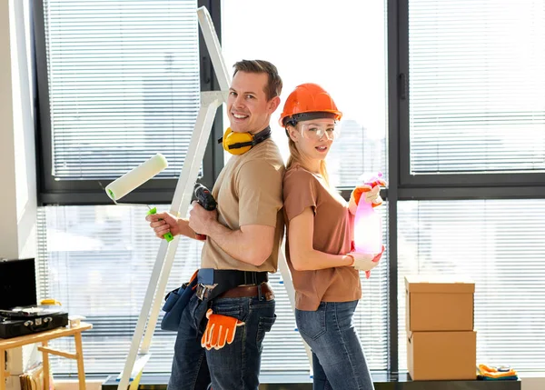 Amistosa pareja caucásica excitada haciendo reparación en nuevo delantal de la casa, sosteniendo herramientas —  Fotos de Stock