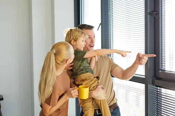 Familia joven con niño diviértete en apartamento nuevo, disfruta de la casa reformada terminada —  Fotos de Stock