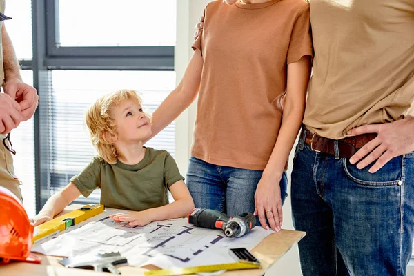 Niño niño está viendo el constructor con interés, los padres tienen hablar sobre la renovación de la casa —  Fotos de Stock