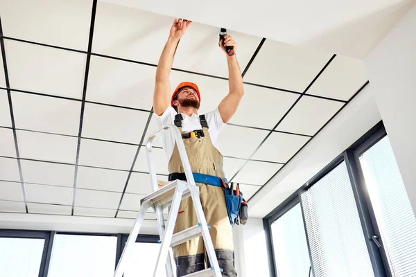 Contratante reparador profissional trabalhando no painel de teto aéreo usando broca de energia — Fotografia de Stock