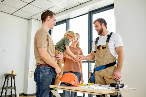 Engraçado criança menino apertando a mão para o homem construtor, divirta-se enquanto discute o plano da casa — Fotografia de Stock