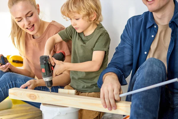 Caring parents teaching little son to repair, use instruments tools, hobby