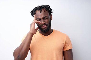 Afro-Amerikan adam baş ağrısı çekiyor, tapınaklara dokunuyor, beyaz tenli.