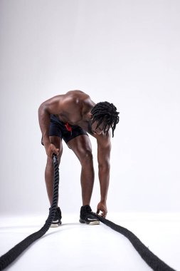 Afro-Amerikalı adam yerden halat alıp eğitime gidiyor, egzersiz yapıyor.