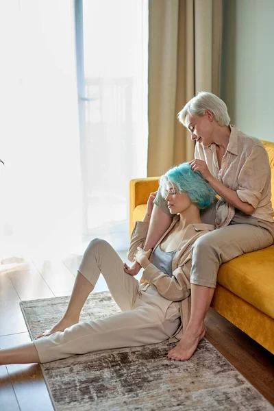 Adoráveis lésbicas tendo descanso em casa no sofá, aproveitando o tempo juntos na sala de estar — Fotografia de Stock