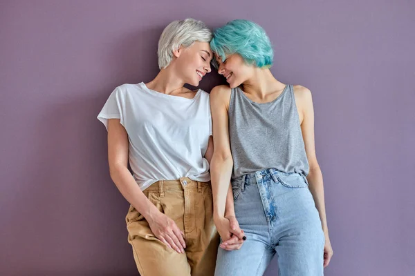 Söta glada kvinnor omfamnar varandra mot pastell lila vägg med kopieringsutrymme — Stockfoto