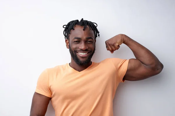 Cara afro-americano positivo em camiseta laranja mostrando bíceps e sorridente, isolado — Fotografia de Stock