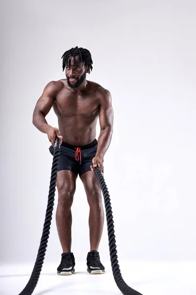 Fekete izmos férfi, nehéz kötelekkel edz. sportos férfi meztelen felsőtesttel — Stock Fotó