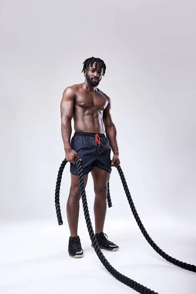 Atleta afroamericano delgado bien construido preparándose para el entrenamiento con cuerdas de batalla, retrato —  Fotos de Stock