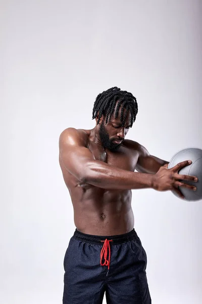 Africano sin camisa Hombre ejercitando con bola de la medicina en estudio sobre fondo blanco — Foto de Stock