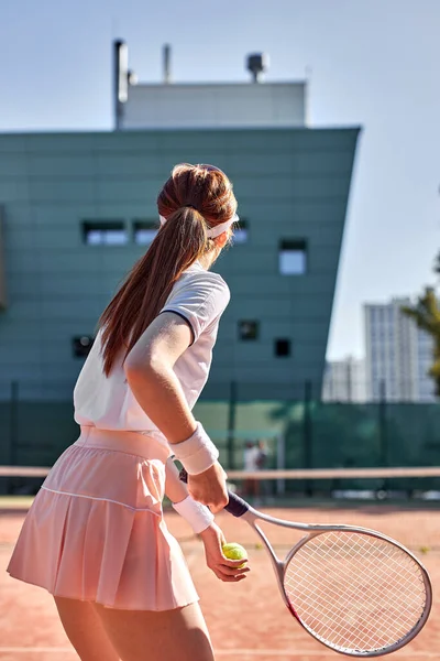 Οπίσθια όψη για αθλήτρια γυναίκα που παίζει τένις σε υπαίθριο γήπεδο, χτυπώντας μπάλα, αθλητική έννοια — Φωτογραφία Αρχείου