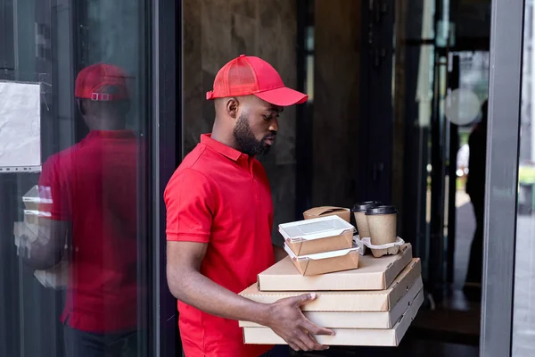 Serviço de entrega de alimentos por correio africano. Correio em uniforme vermelho com caixas de pizza — Fotografia de Stock