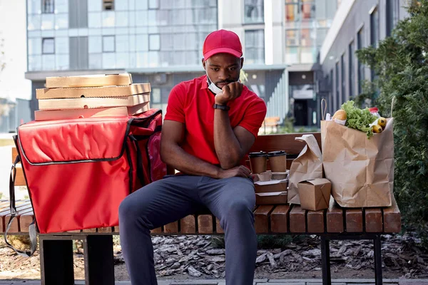 Sad Courier with thermal backpack delivering fresh lunches to clients, sit waiting — Stock Photo, Image