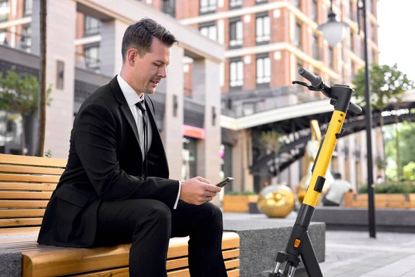 ハッピーcaucasian 30代男性チェックスマートフォン中にe-scootler乗りで大都市 — ストック写真
