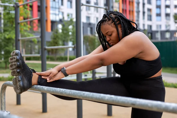 アフリカ系アメリカ人の太った女性が足を伸ばしヨガやスポーツワークアウトの前に足を暖める — ストック写真