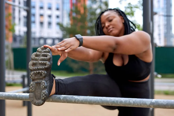 Μαύρη αμερικανίδα χοντρή γυναίκα που τεντώνει τα πόδια, ζέσταμα πόδια πριν από γιόγκα ή αθλητική προπόνηση — Φωτογραφία Αρχείου