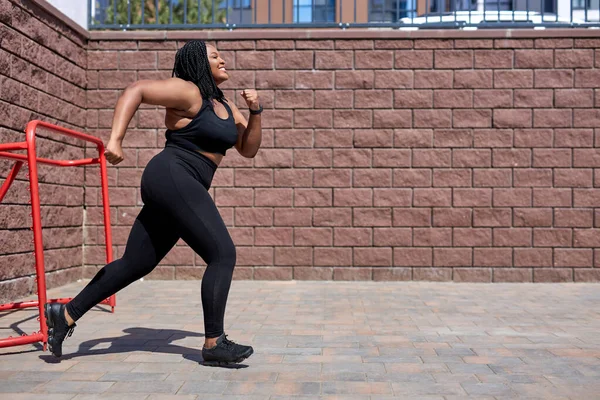 Afrikalı bir kadın, şehirde kalori yakmak için kardiyo antrenmanı yaparken koşuyor. — Stok fotoğraf