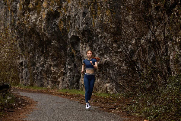 Running woman athlete sport concept. Female redhead runner exercising in mountain — Stock Photo, Image