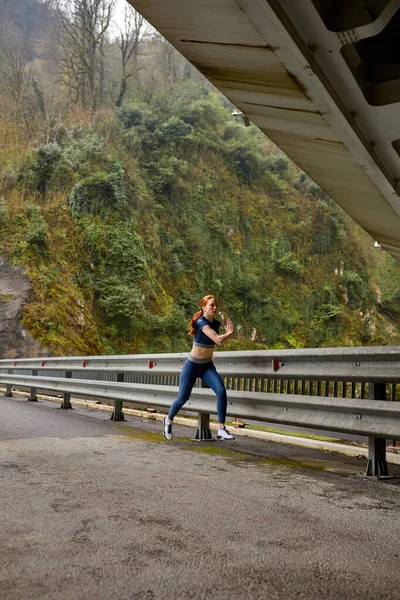 Young woman running jogging fast outdoors. Female athlete exercising on modern bridge. — Stock Photo, Image