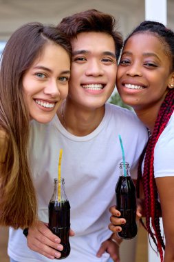 Arka bahçedeki barbekü partisinde çeşitli arkadaşlar, kameraya içeceklerle poz veriyorlar.