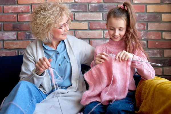 Lachende liefdevolle senior oma is het onderwijzen van kleine dochter breien — Stockfoto