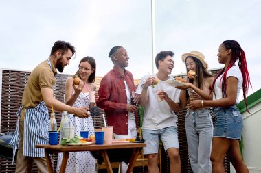 Bir grup mutlu arkadaş arka bahçedeki barbekü partisinde eğleniyor.