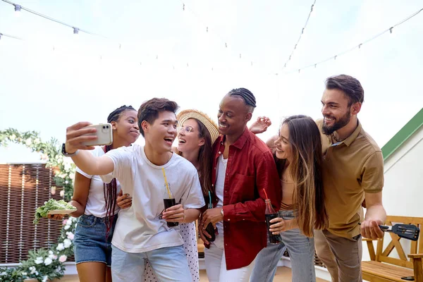 Çoklu etnik gruplar arka bahçede Patty 'nin tadını çıkarıyor, akıllı telefondan fotoğraf çekiyorlar. — Stok fotoğraf