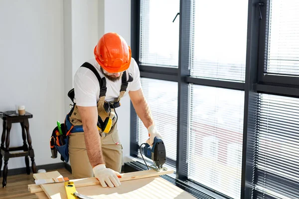 Zelfverzekerde constructeur werkend met een elektrische decoupeerzaag hout zagen met zaag — Stockfoto