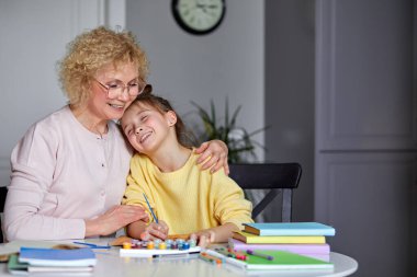 Güzel torun ve büyük anne evde oturup ödev yapıyor.