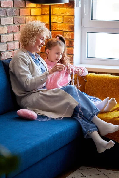 Vaardige oma zitten op de bank met dochter, leren hoe om te breien, thuis — Stockfoto
