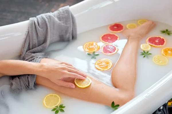 Donna snella irriconoscibile gode di bagno con latte e succosi frutti esotici. vista laterale — Foto Stock