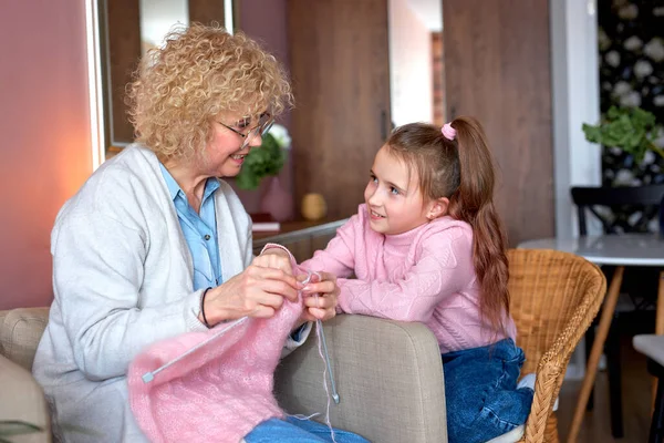 Schattig aangenaam Kaukasisch meisje zitten in de buurt van oma kijken haar breien — Stockfoto