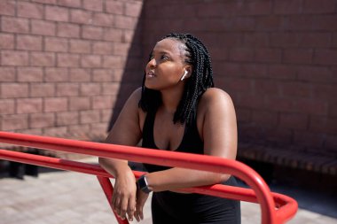 Karışık ırk. Siyah spor elbiseli hoş bir kadın. Dinleniyor.