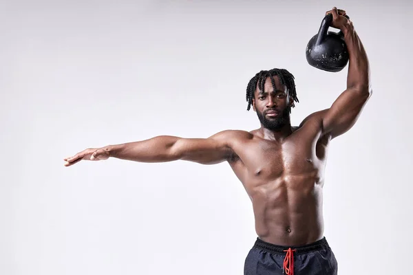 Deportista musculoso, chico sin camisa levantando kettlebell aislado sobre fondo blanco del estudio. — Foto de Stock