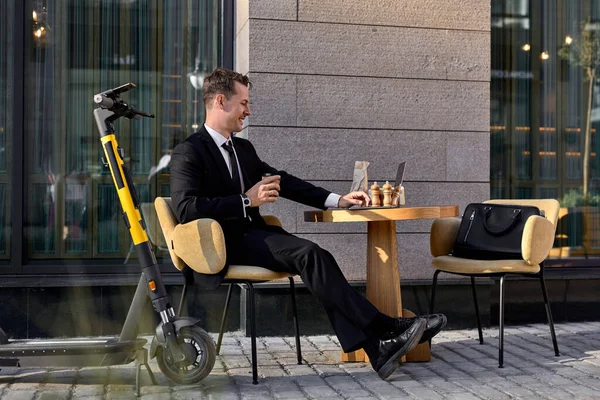 正ビジネス男でフォーマルスーツ座って作業上のラップトップで屋外カフェ — ストック写真