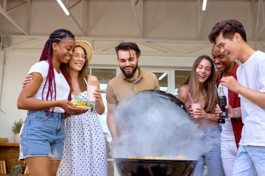 Bir grup genç arkadaş barbekü ızgarası açıyor ve akşam yemeği hazırlıyorlar.
