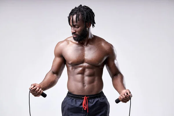 Retrato del hombre africano sudoroso sin camisa sosteniendo la cuerda en las manos, preparándose para saltar — Foto de Stock