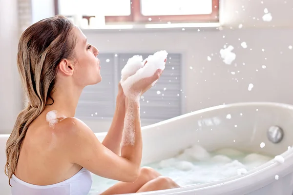 Vista lateral sobre mujer caucásica relajándose con placer en baño de espuma con burbujas —  Fotos de Stock