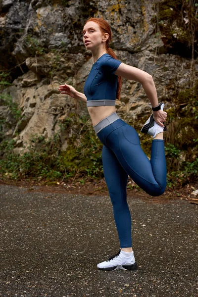 Young woman posing in fitness outfit. Portrait of young sports woman  relaxing outdoors after workout. Female jogger in bright sportswear smiling  looking away, advertising for sports Stock Photo