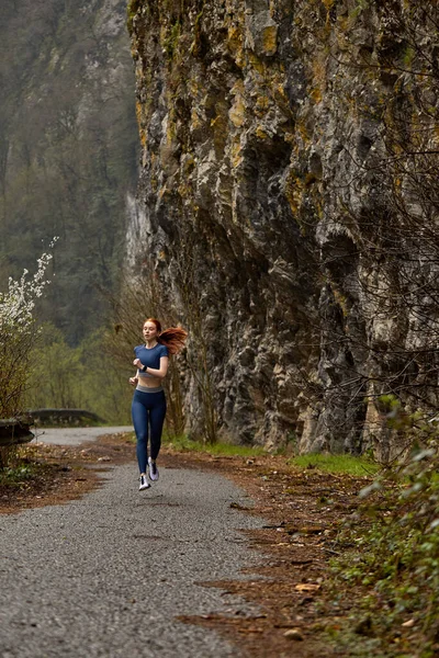 Koşu yapan kadın sporcu konsepti. Dişi kızıl saçlı koşucu dağda egzersiz yapıyor. — Stok fotoğraf