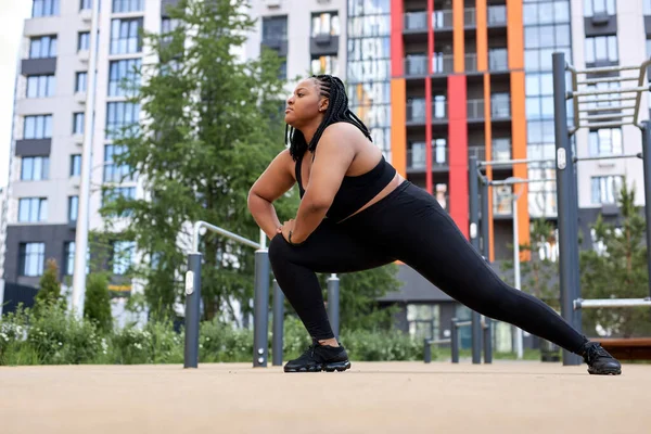 Obez şişman Afrikalı kadın antrenmandan önce spor alanında esneme egzersizleri yapıyor. — Stok fotoğraf