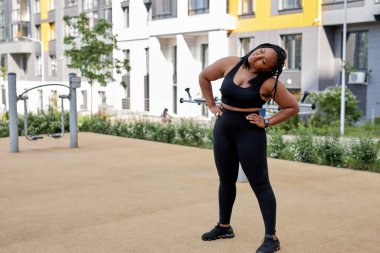 Kadın, koşmadan önce kaslarını ısıtıyor. Açık havada koşuyor, yandan bakıyor.