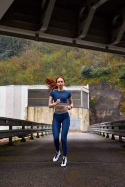 Genç, kendine güvenen bayan koşucu koşuyor, sakin ve güzel atletik kadın.