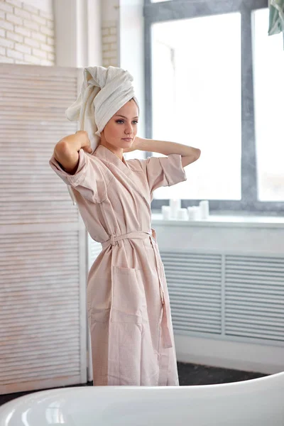 Good-looking caucasian female is wrapping hair in towel after taking bath — Stock Photo, Image