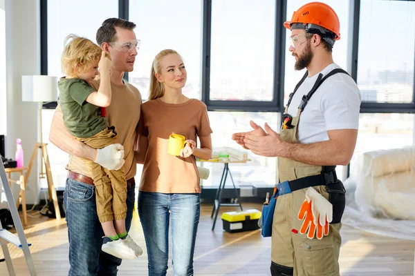 Construtor reparador explicando futuros planos de projeto da casa para a família com a criança. — Fotografia de Stock