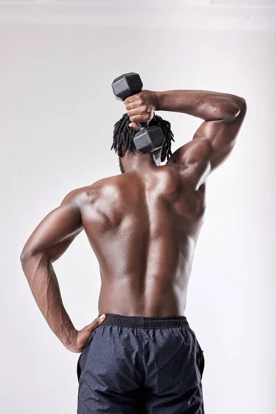 Homem afro-americano jovem masculino segurando halteres no fundo branco. vista traseira — Fotografia de Stock