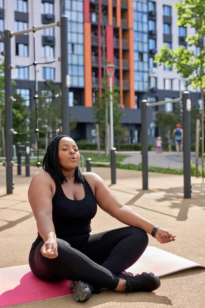 Yoga, farkındalık, sağlıklı yaşam tarzı kavramı. Genç şişman Afrikalı kadın dışarıda meditasyon yapıyor. — Stok fotoğraf