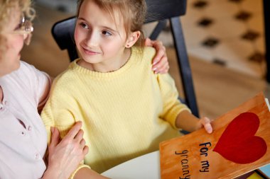 Orta yaşlı, hoş bir kadın, kızından el yapımı aşk kartı almaktan mutlu.