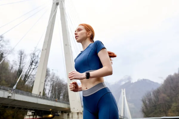Zicht van beneden op vrij Kaukasische vrouwelijke hardloper jogger in beweging, kijken naar kant — Stockfoto