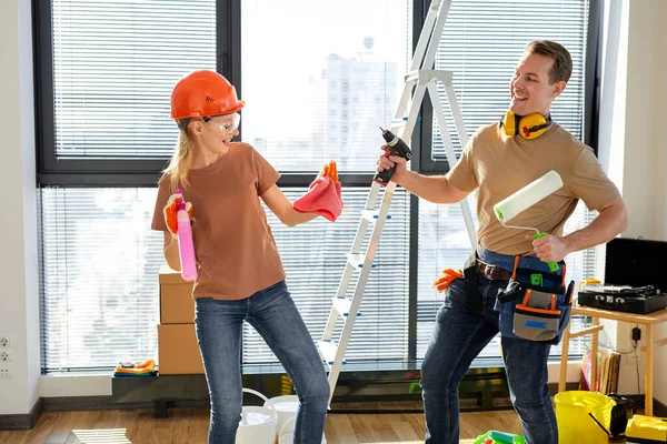 Pareja alegre bailando, divirtiéndose después de hacer reparaciones, pintando paredes en un nuevo hogar —  Fotos de Stock